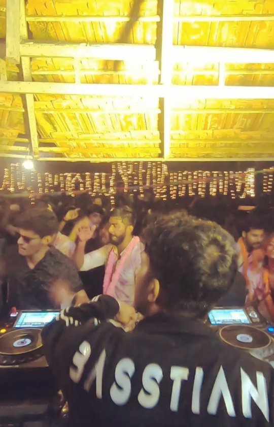 Basstian am DJ-Pult, von hinten fotografiert, vor einer feiernden Crowd